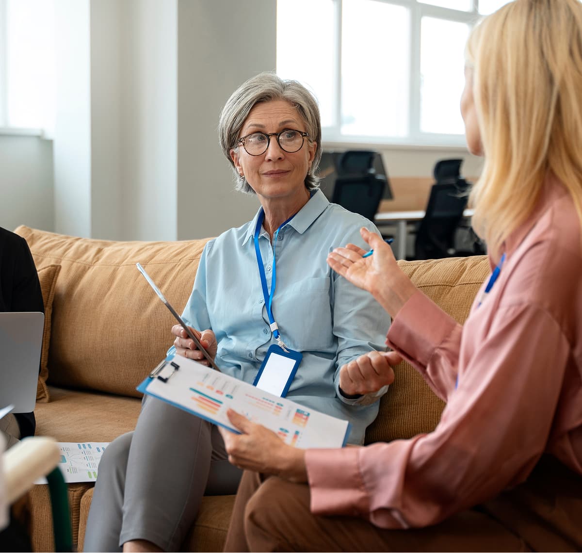 Two colleagues reviewing meeting notes and a printed report together during a discussion