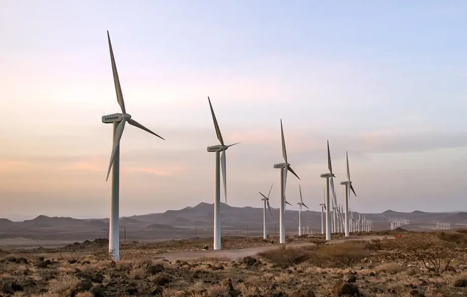 Vestas wind turbines stretching across a rocky landscape at sunset.