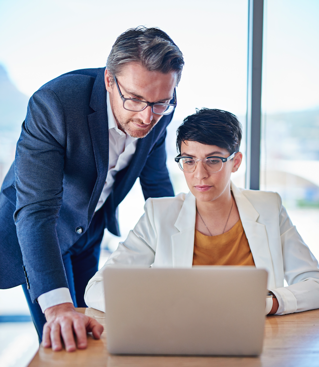 Two business professionals reviewing meeting documentation on a laptop